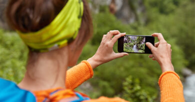 backwards shot of woman tourist makes photo of river in ravine on smartphone device for posting in social networks